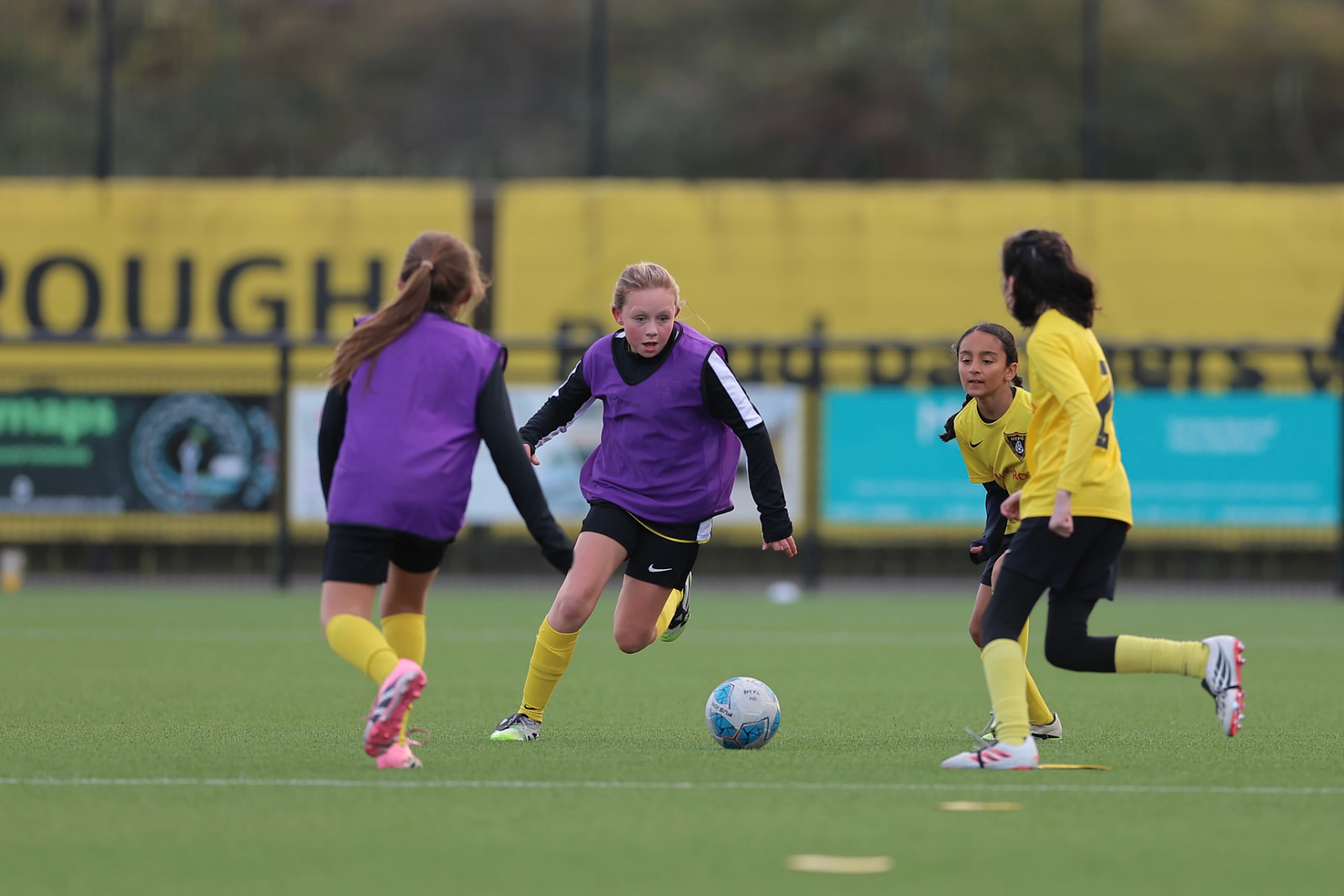 Youth footballers playing in yellow and purple kits