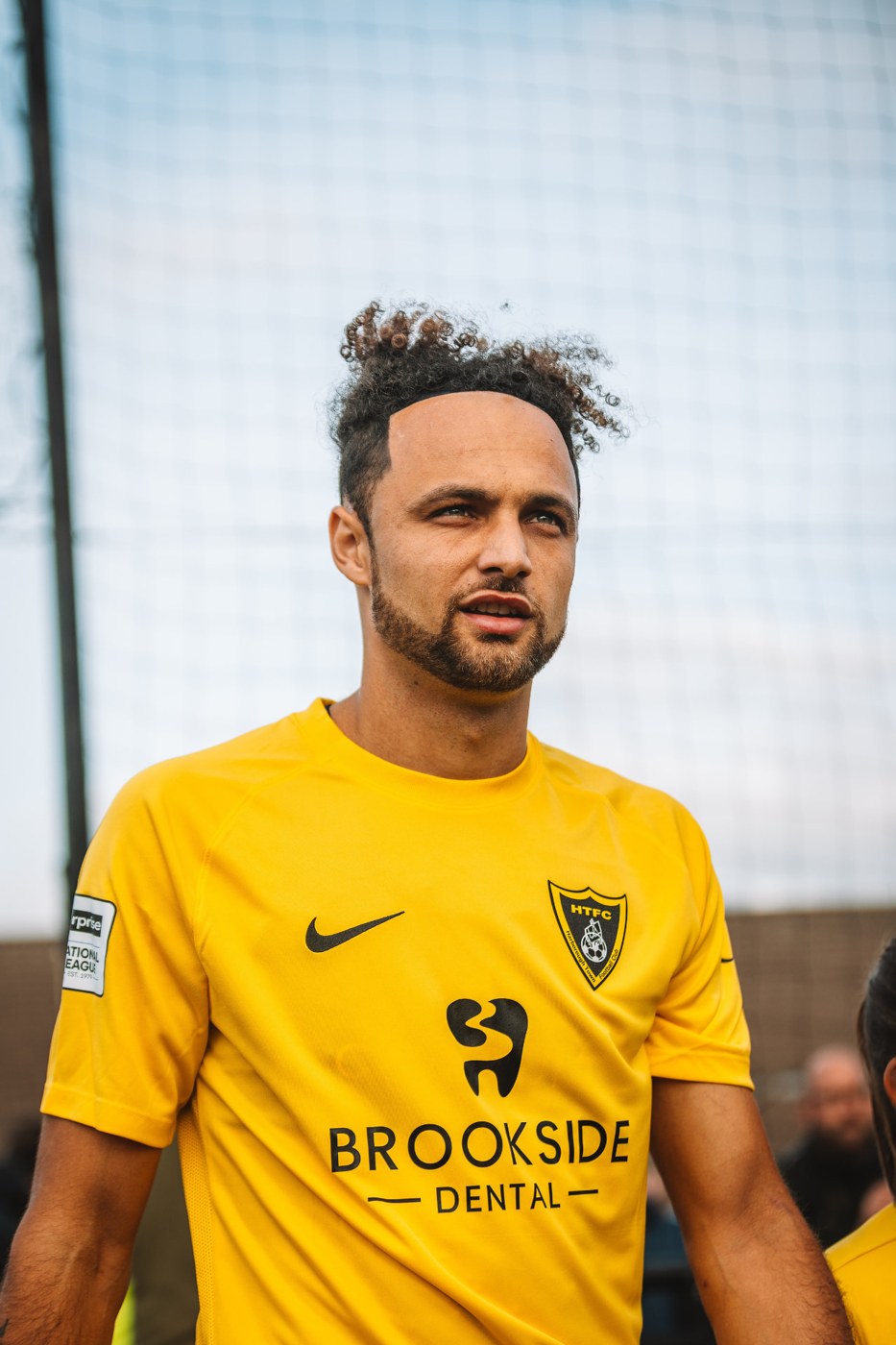 Harborough Town player wearing the yellow Brookside Dental home shirt